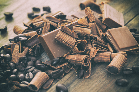 Chocolate pieces with cocoa and coffee beans on a wooden tableの写真素材