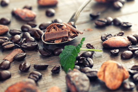 Chocolate pieces with cocoa and coffee beans on a wooden tableの写真素材