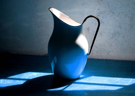 Blue metal jug for water on a wooden tableの写真素材