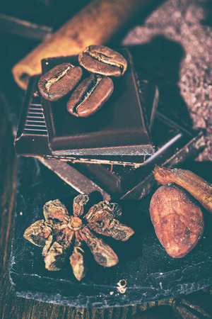 Broken dark chocolate, cocoa powder and coffee beans on a wooden tableの写真素材