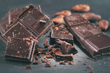 Broken dark chocolate and coffee beans on a wooden tableの写真素材