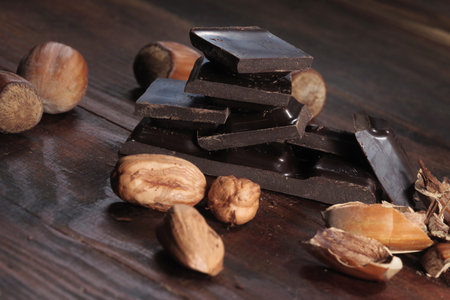 Dark chocolate and hazelnuts. Broken chocolate bar on black kitchen tableの写真素材