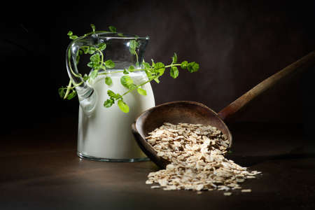 Oatmeal in a wooden bowl, oatmeal and cup of milk on the table. Healthy eating