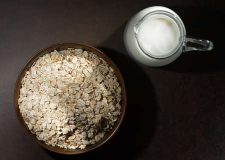 Oatmeal in a wooden bowl, oatmeal and cup of milk on the table. Healthy eating