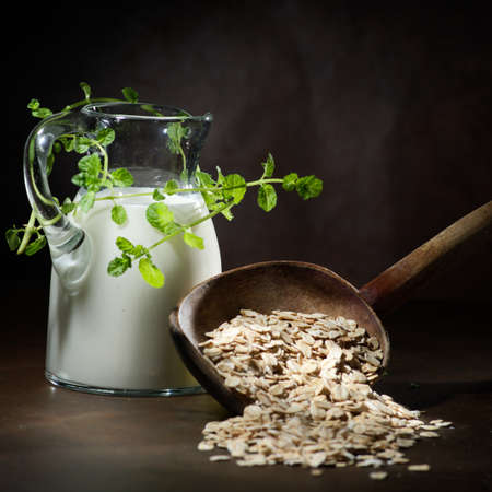 Oatmeal in a wooden bowl, oatmeal and cup of milk on the table. Healthy eatingの写真素材