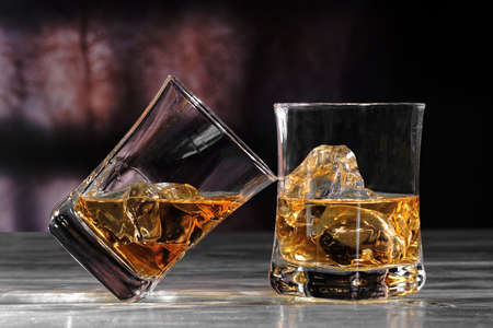 Glass of amber scotch whiskey and ice on a dark backgroundの写真素材