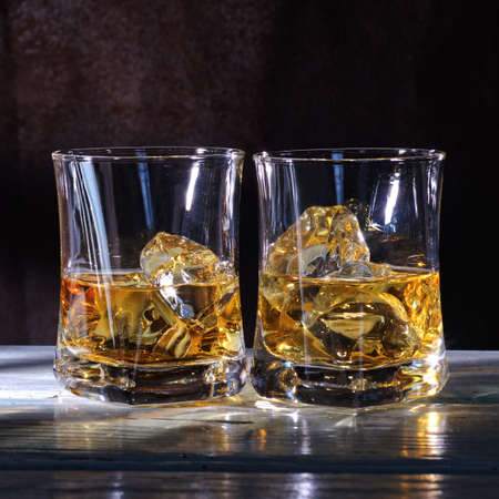 Glass of amber scotch whiskey and ice on a dark backgroundの写真素材