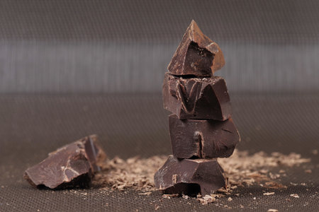Broken dark chocolate and cocoa powder on a tableの写真素材
