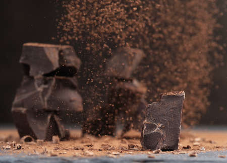 Broken dark chocolate and cocoa powder on a table