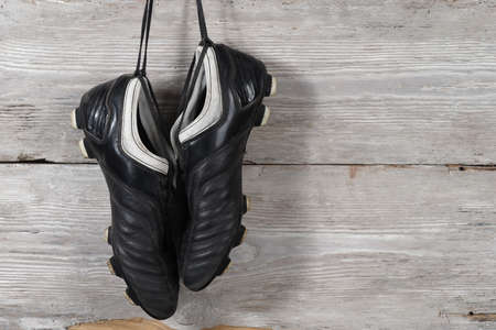 A pair of soccer boots hanging on a wooden wall. The end of the football careerの写真素材