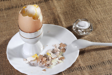 Boiled egg on a white porcelain eggcup with broken eggshell