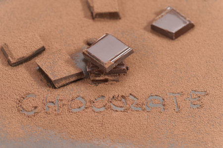 Chocolate powder and pieces of chocolate on grey background, closeupの写真素材