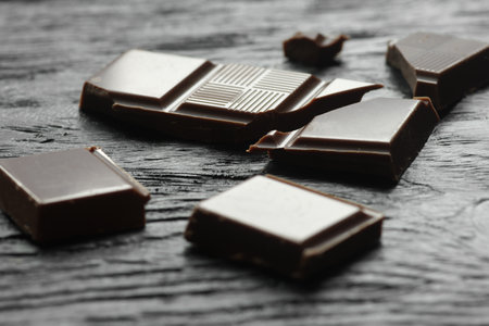 Broken chocolate bars on wooden background, closeup. Sweet food