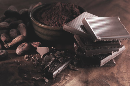 Chocolate, cocoa beans and powder on a wooden background. Selective focus. Toned.