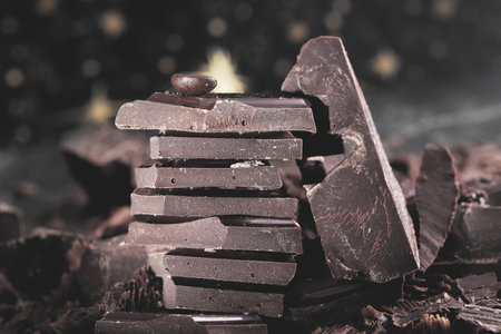 Broken dark chocolate on black background. Selective focus. Toned.の写真素材