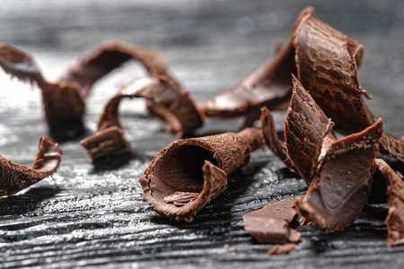 Broken chocolate curls on wooden table, closeup. Delicious dessertの写真素材