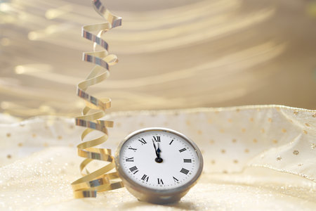 Vintage silver pocket watch with golden ribbon and streamer on bokeh backgroundの写真素材