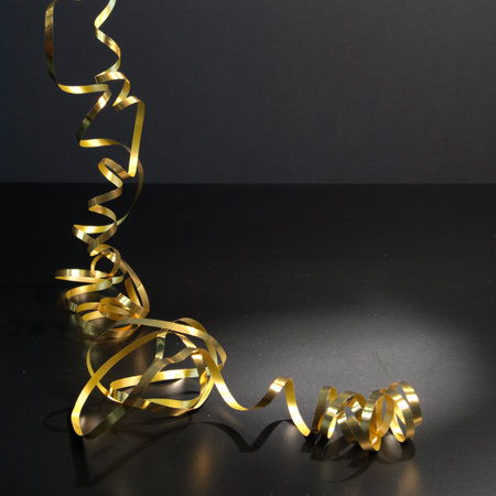 Golden serpentine on black background. Festive decoration for New Year and Christmas.の写真素材