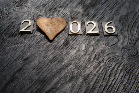 Happy New Year with heart shaped cookie on a wooden background.