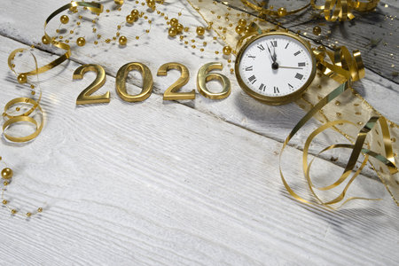 New Year's Eve celebration concept. Clock and golden numbers on white wooden background.
