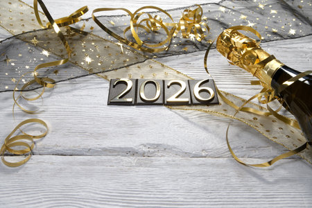 New Year's Eve celebration with champagne and golden ribbons on wooden background