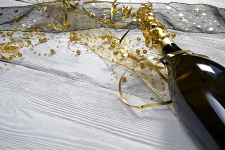 bottle of wine and golden confetti on a white wooden backgroundの写真素材