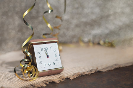 Vintage gold alarm clock on sackcloth with golden ribbons and tinselの写真素材