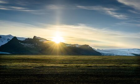 Sunset in Iceland over a mountain range with glacier in backgroundの写真素材