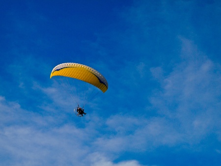 A Paraglider flies in the blue sky