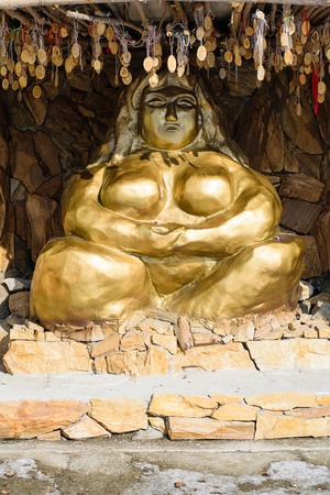 Statue of a golden woman sitting in a lotus pose with ethnic ornaments. The mother of all people on earthの写真素材