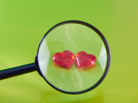 Two red glass hearts stacked side by side on a green background. view through a magnifier. Valentine's Day. love symbol.の写真素材