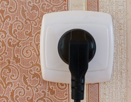Black electrical plug plugged into a white outlet. electricity. nutrition. energy. launch.の写真素材