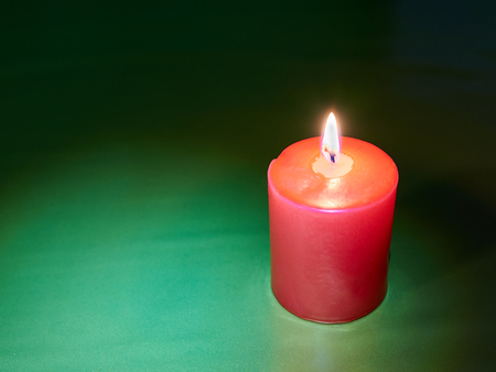 Red wax festive romantic burning candle on a green decorative background. love symbol. festive mood. romantic dinner. copy spaceの写真素材