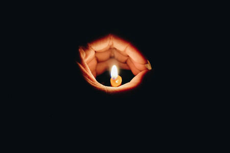Hand and candle in the dark