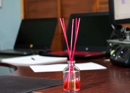 Scent glass bottle with pink sticks on a desk. Home Office.の写真素材