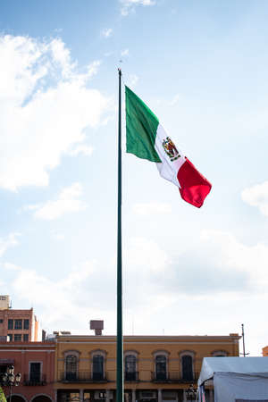 Vertical image of the flag of Mexico on a flagpole. Downtown Leon, Guanajuato. Urban concept.の写真素材