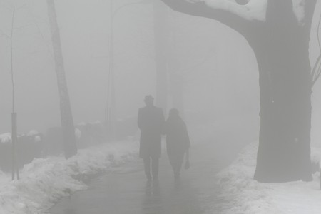 elderly man and woman walking in fogの写真素材