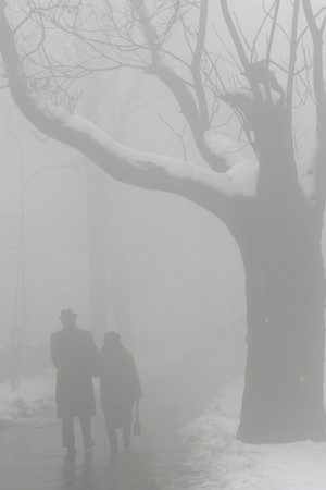 elderly man and woman walking in fogの写真素材