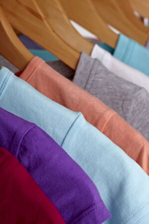 close up of t shirts on cloth hangers in row