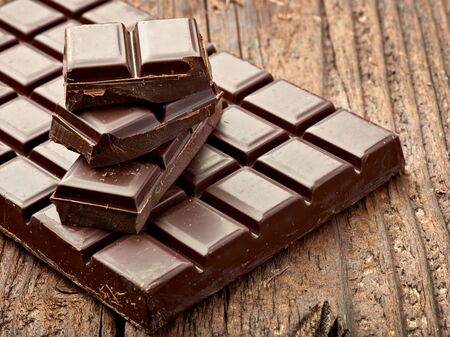 close up of chocolate pieces on  wooden background