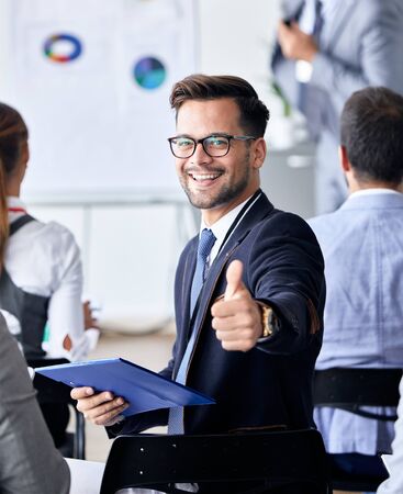 A portrait of a young smiling businessman  a meeting and presentation in the office. Business conceptの写真素材