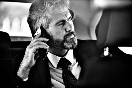 senior businessman sitting on the back sit of a luxury car