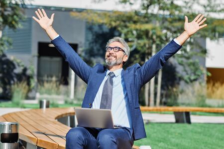 A portrait of a senior businessman celebrating a victory relaxingの写真素材