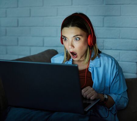Portrait of a young woman looking at monitor by night, glowing light