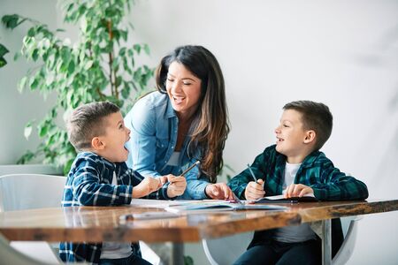 mother teaching sons and helping with homework at home