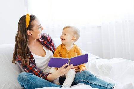 Portrait of a mother and son reading a book and  having fun together at homeの写真素材
