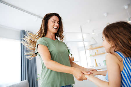 mother and daughter dancing and having fun at homeの写真素材