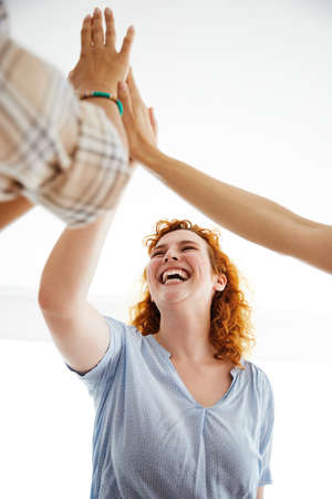Aportrait of young business woman celebrating with high five in the office or in classroom