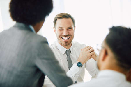 A portrait of a young smiling businessman  during a meeting  in the office. Business conceptの写真素材