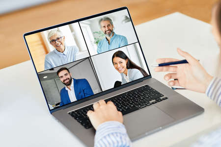 Back view of female employee speak talk on video call with colleagues on online briefing